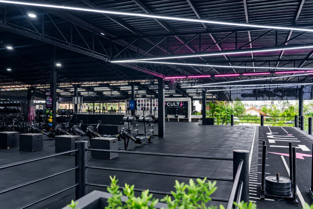Open training floor with lifting rigs, exercise stations and a marked track.