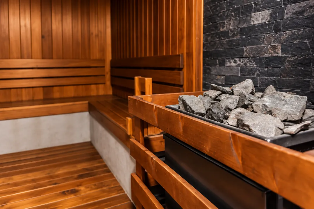Wooden sauna with benches and a stone heater.